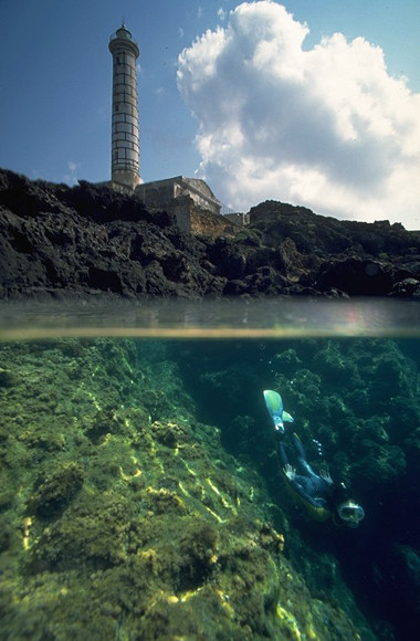 Subacqueo nelle acque trasparenti sotto il faro di Punta Gavazzi